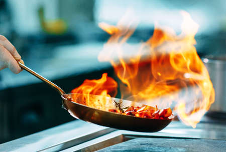 Poêle d'où jaillit du feu d'aliments en cuisant